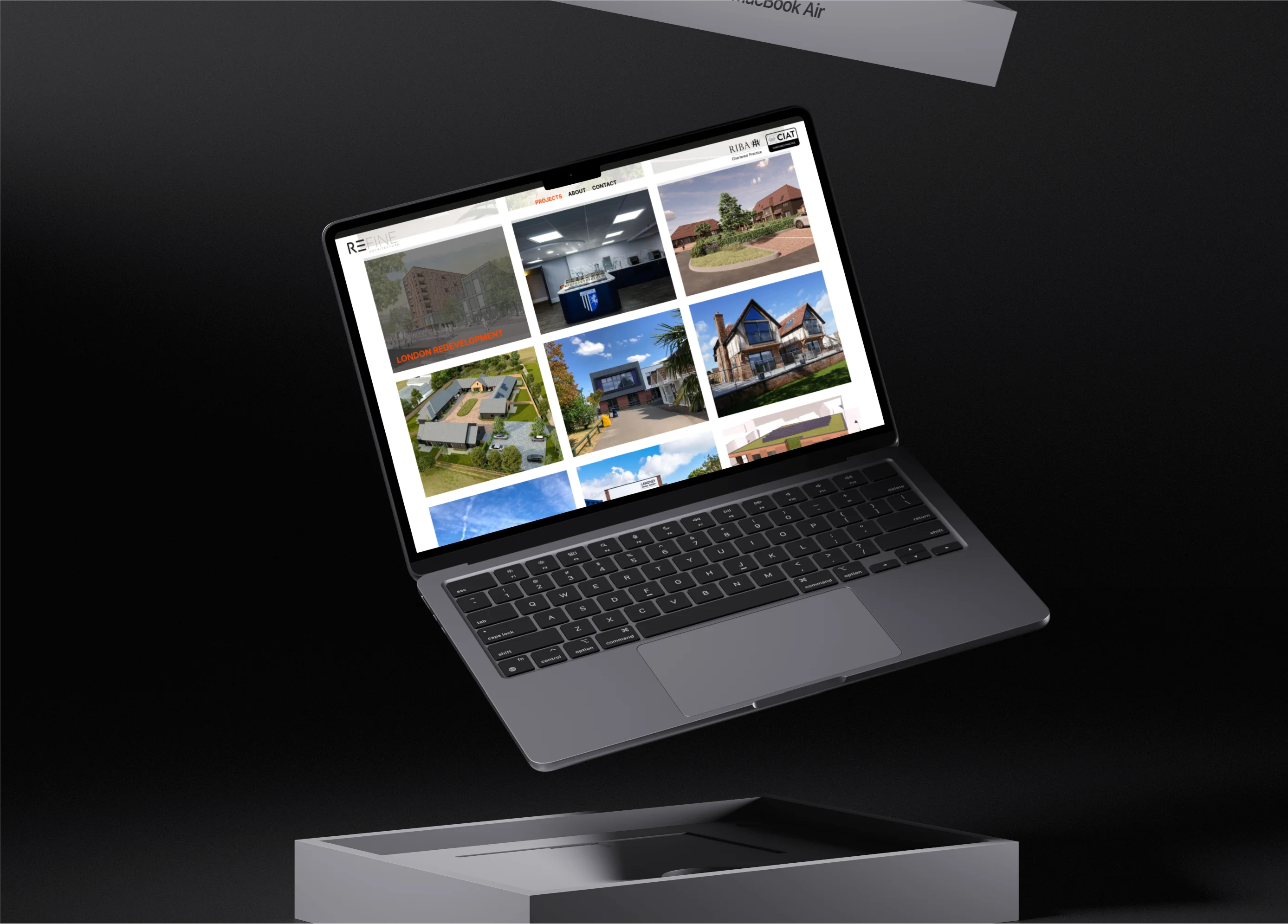 An open laptop floating above its box on a dark surface displaying an architecture project gallery with building images.