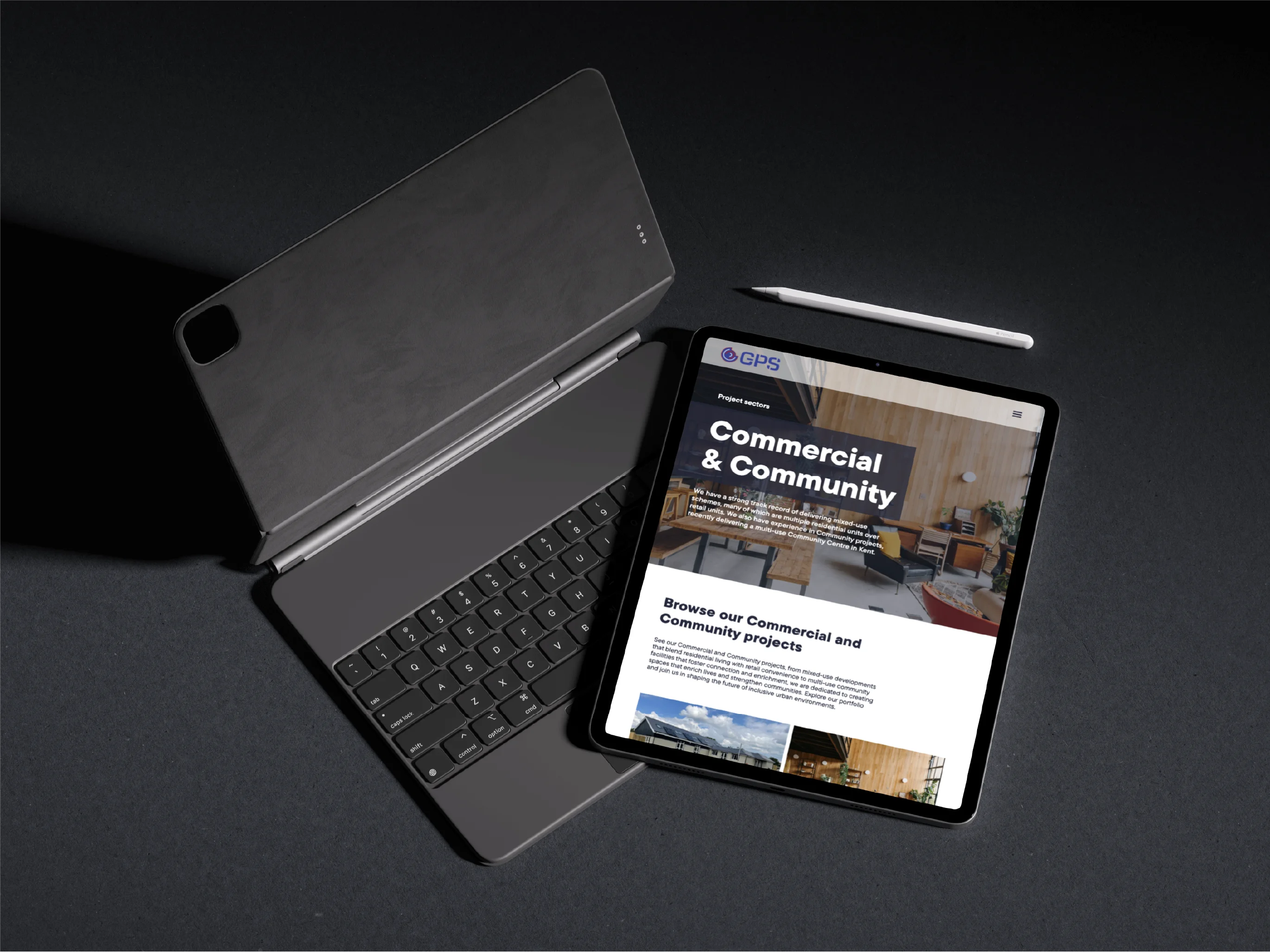 Tablet with keyboard case and stylus on dark surface displaying a webpage about Commercial & Community projects.