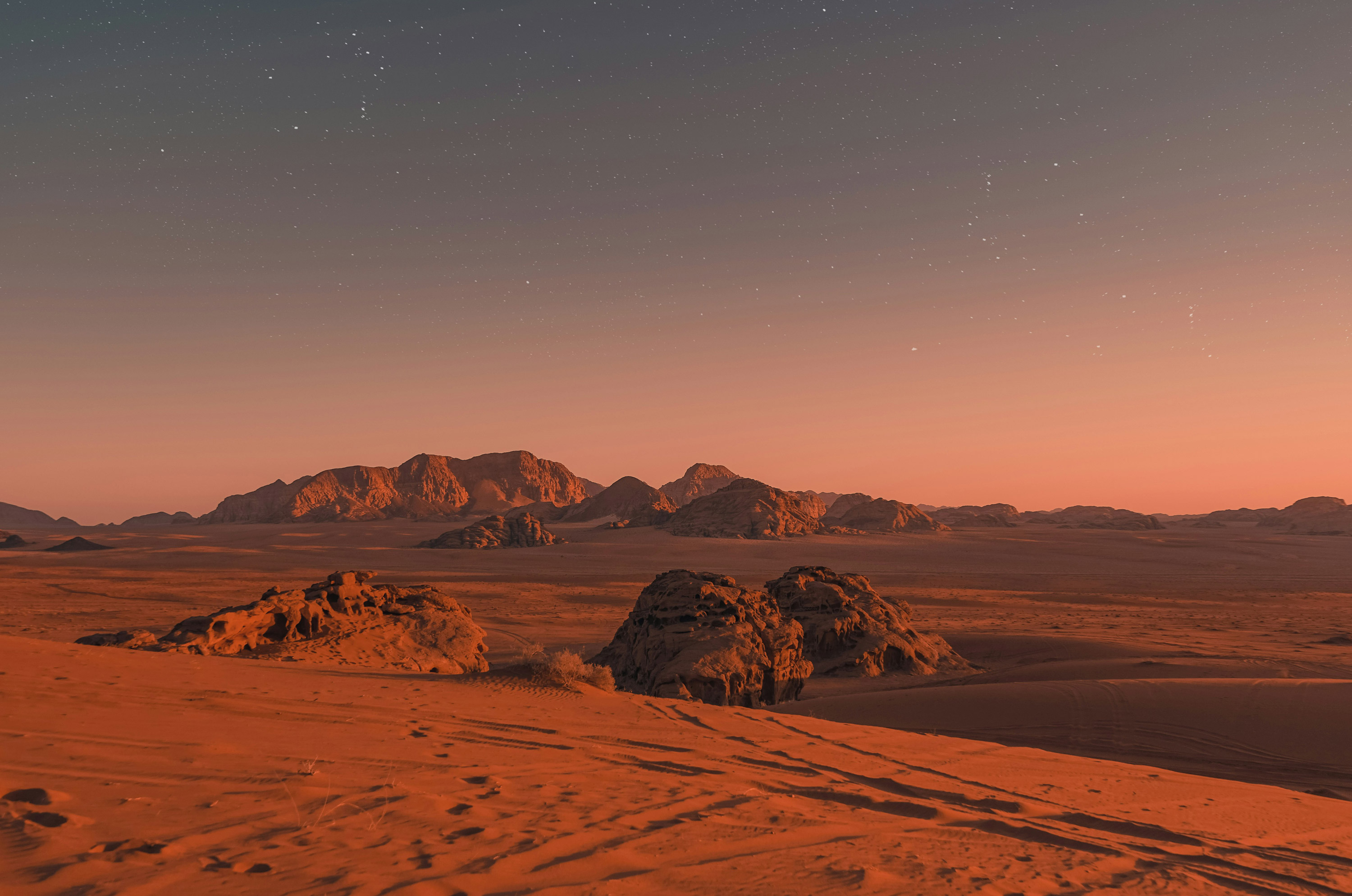 Mars landscape of vibrant sand with rocky cliffs dotting an orange and blue horizon.