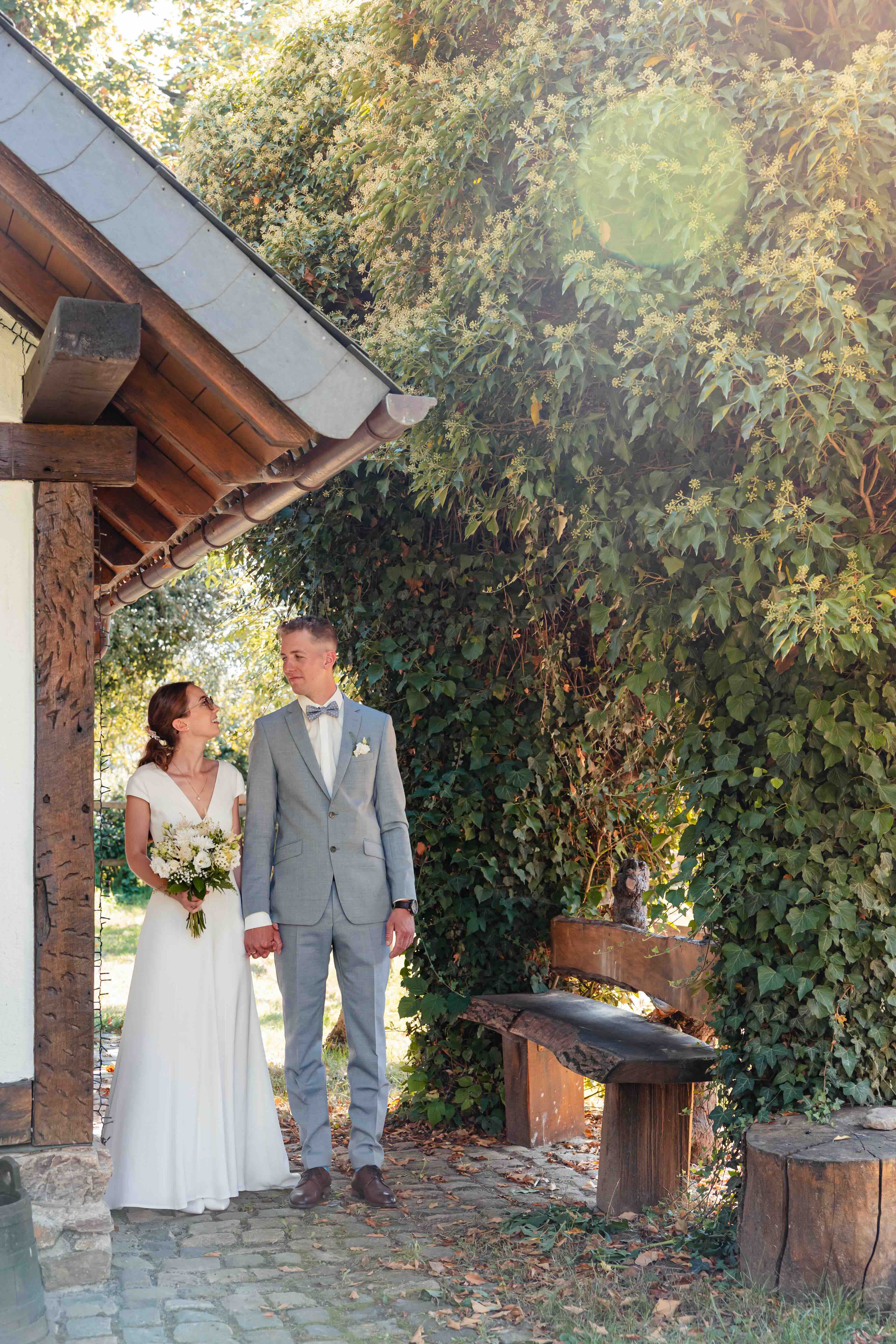bride and groom walking through a garden with a gazebo