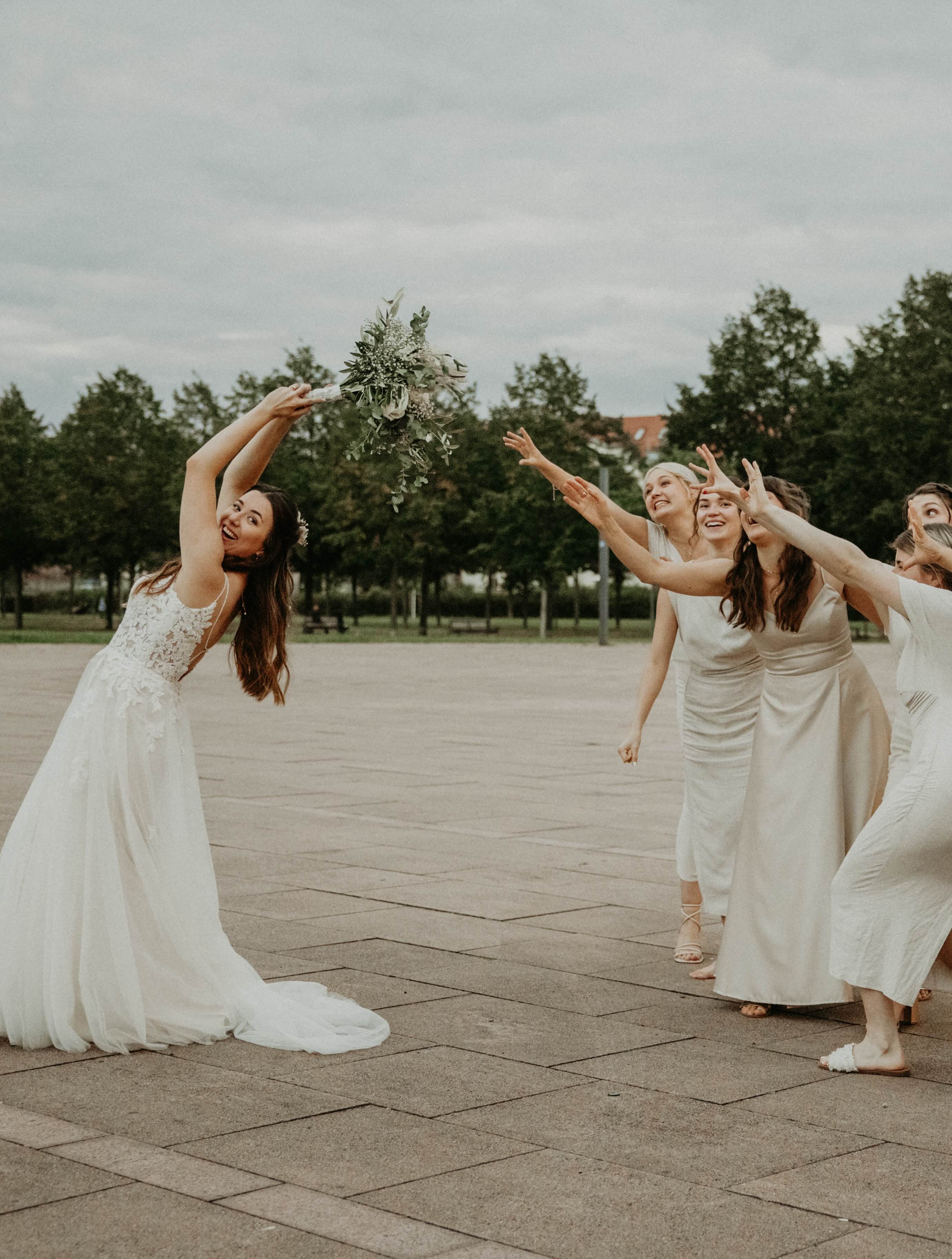bridesmaids and bridesmaids dancing in a courtyard with trees in the background