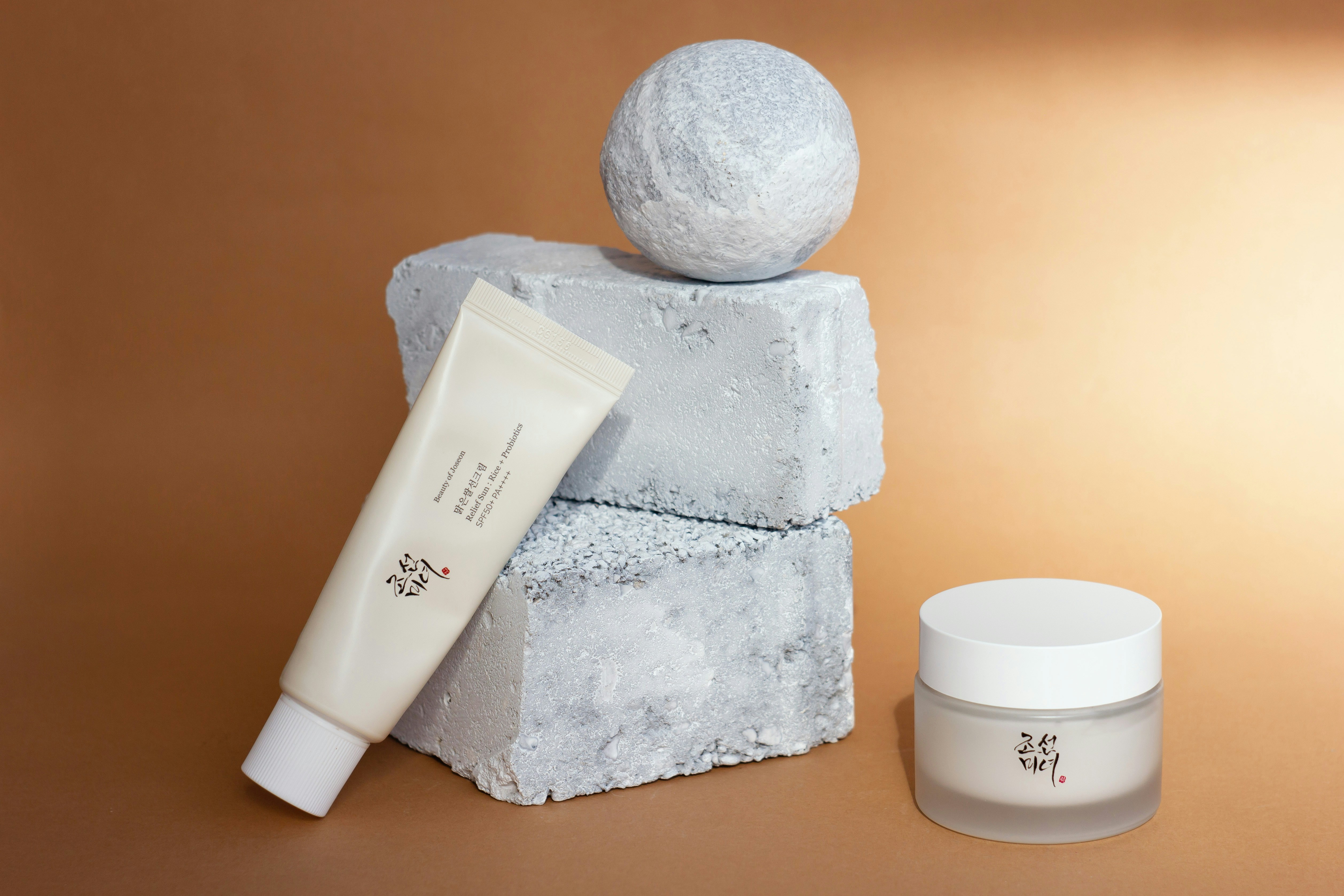 Produits de soin pour la peau, incluant un gommage exfoliant et une lotion hydratante, joliment disposés sur une surface en marbre.