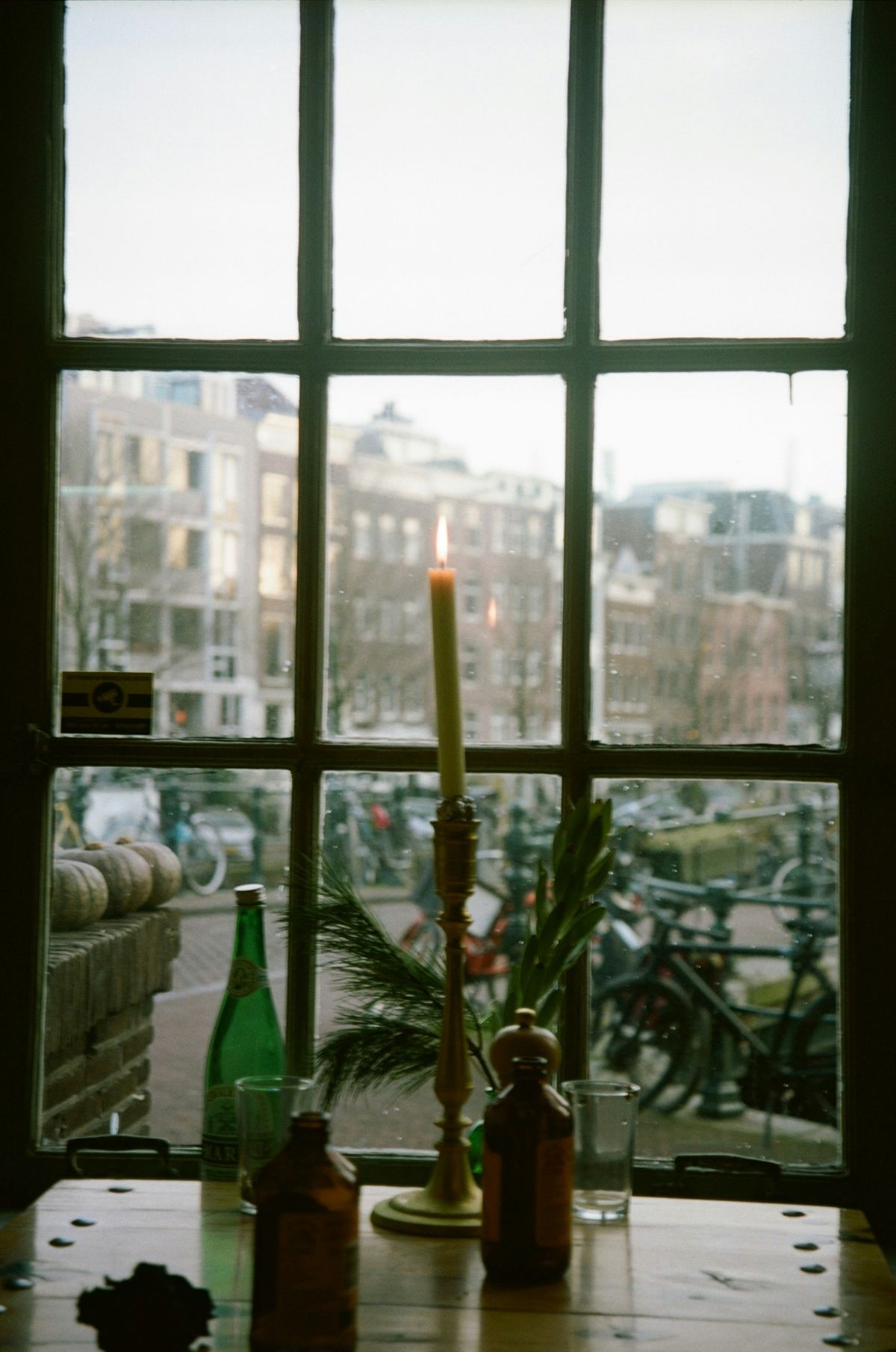 Soft towels, a burning candle and a small green plant on a wooden shelf