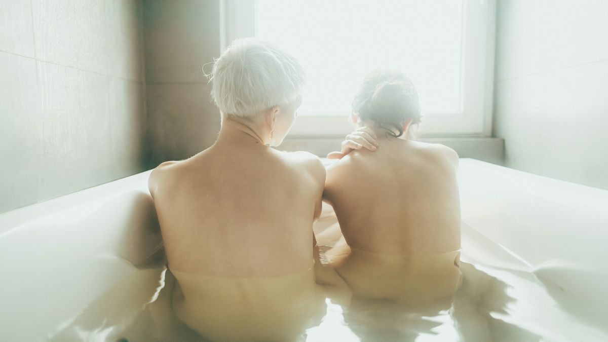 Two people receiving a massage simultaneously in the same room with towels and flowers