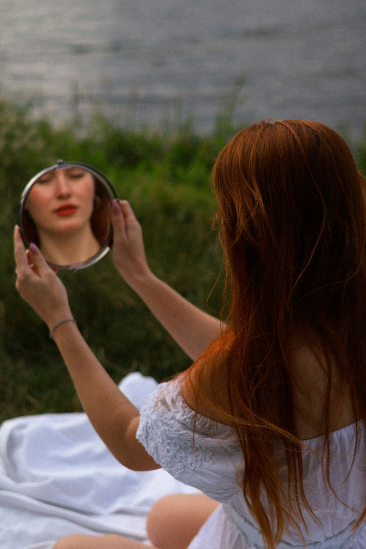 Close up of a woman applying moisturizer to her face looking in a mirror
