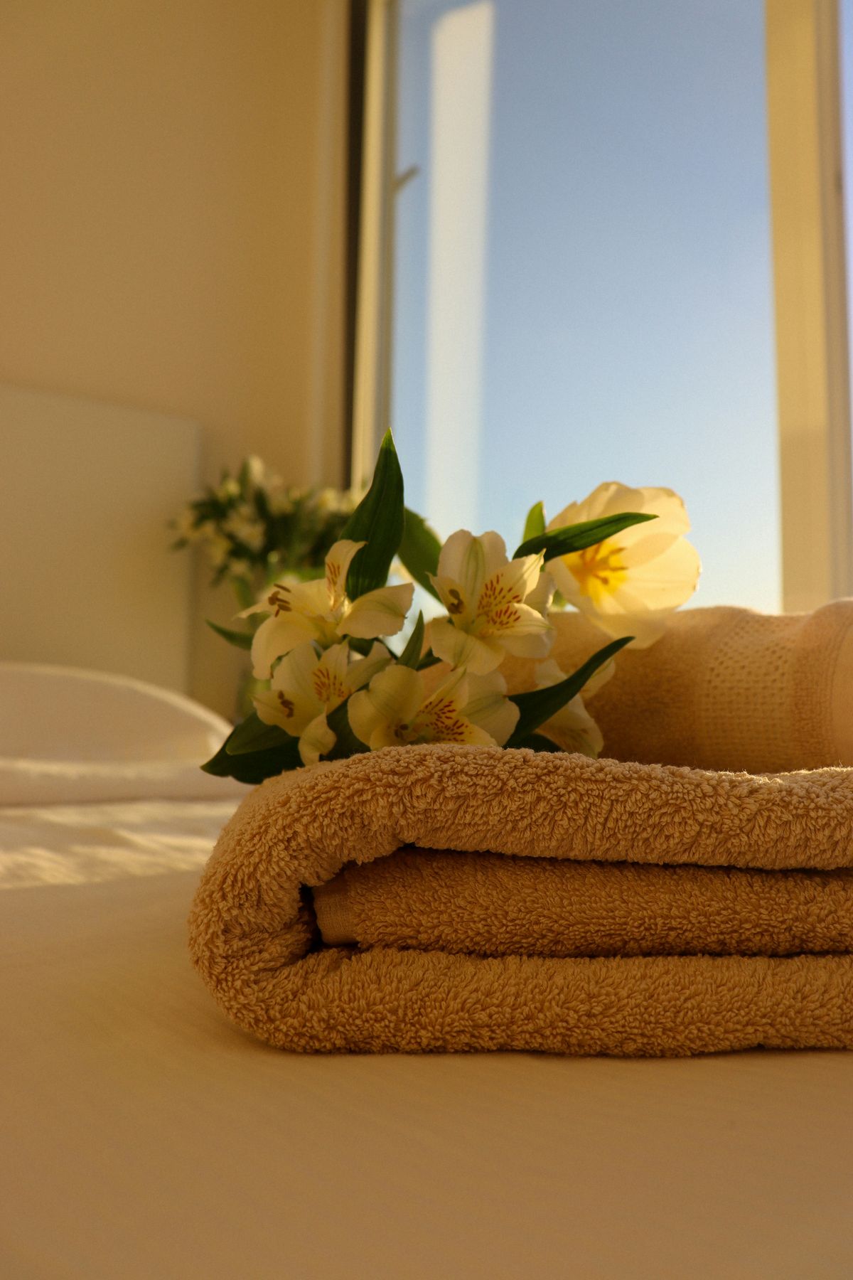 A relaxed woman wrapped in a white towel sitting on a spa bed, looking peaceful