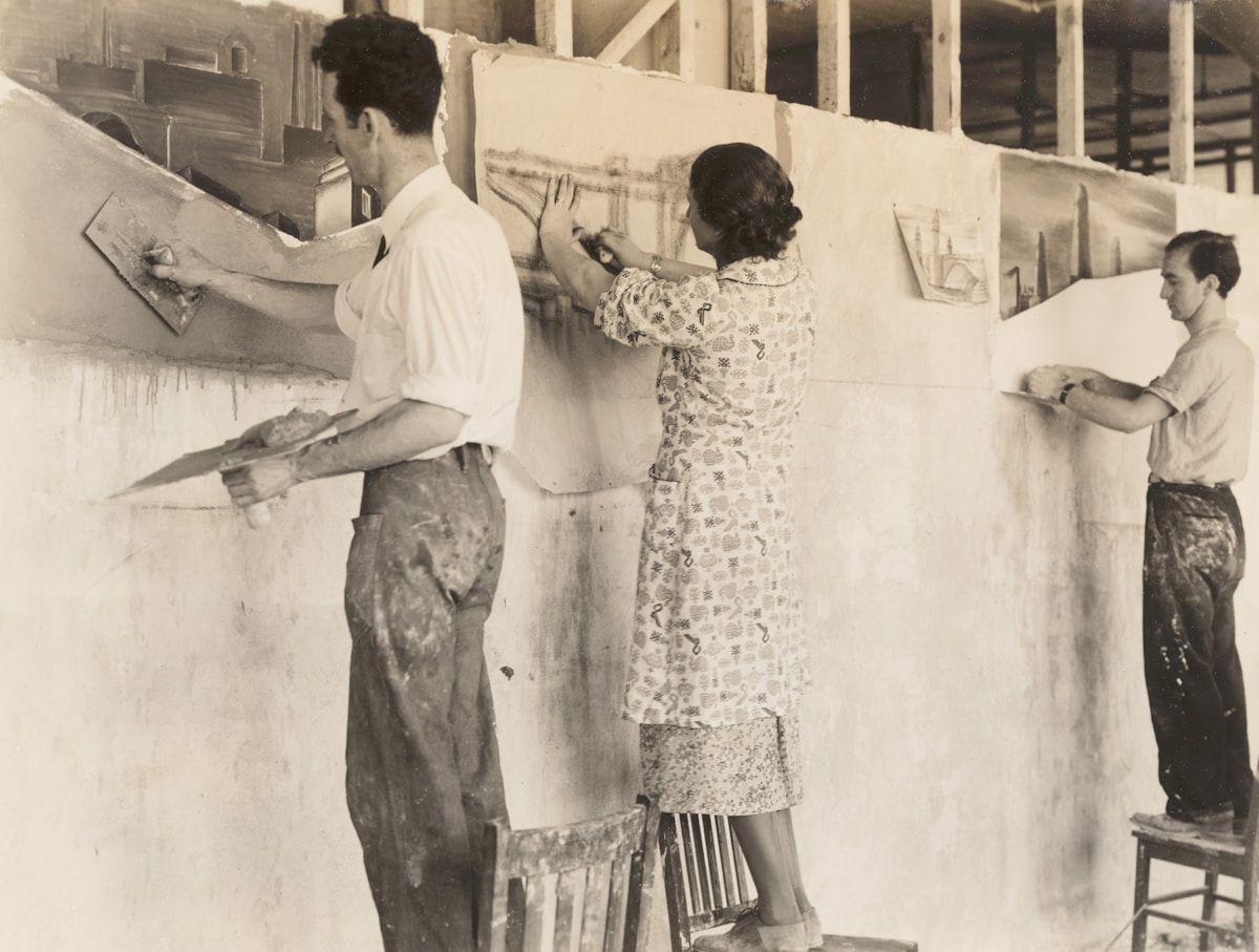 Artists apply plaster to a large mural.