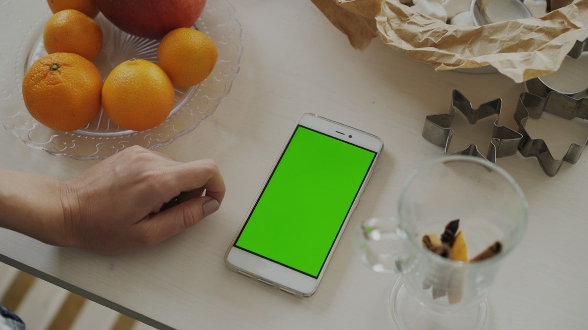 Smartphone with green screen near fruit and cookie cutters