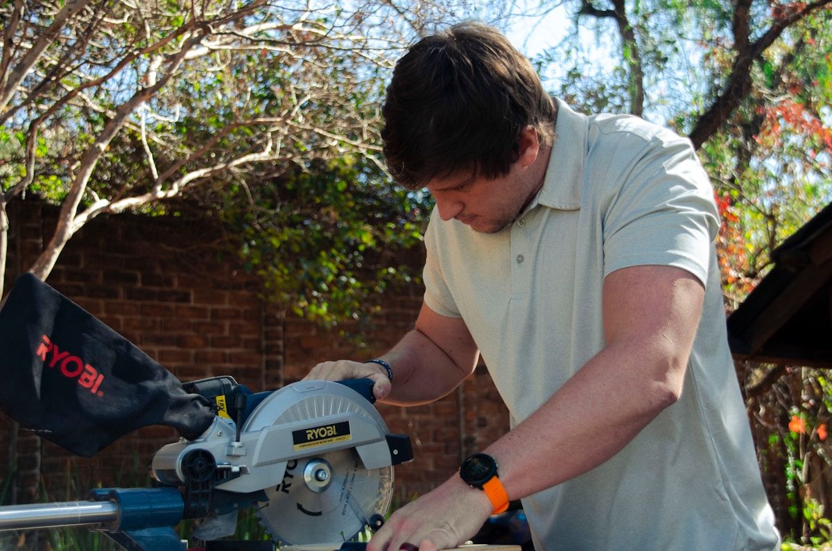 a man using a circular saw to cut a piece of wood
