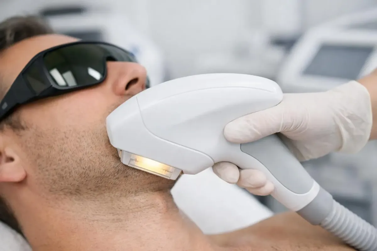 Professional aesthetic practitioner performing IPL hair removal treatment on client's leg in modern Swiss beauty clinic, close-up showing handheld IPL device against skin with safety goggles visible, clinical lighting highlighting treatment precision