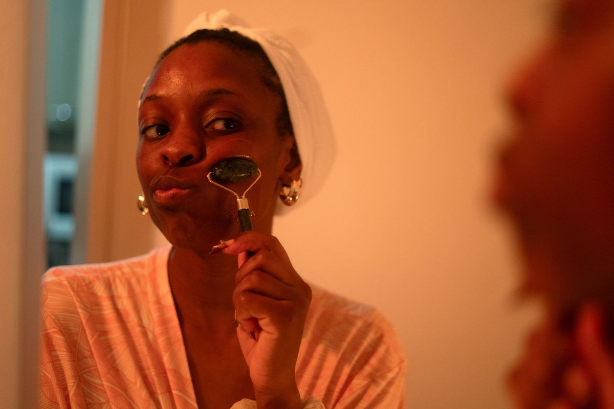 Femme afro-américaine appliquant du maquillage dans un éclairage chaud.