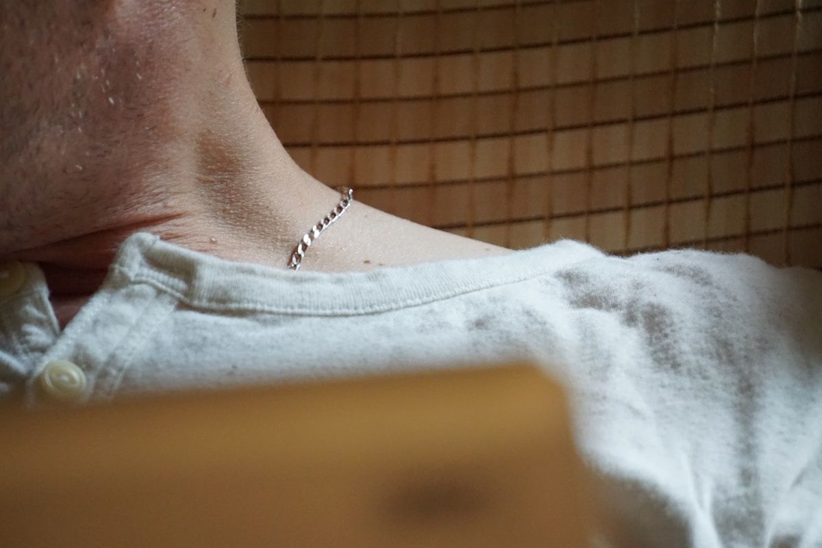 Bracelet en argent sur le poignet d'une personne portant un vêtement blanc.