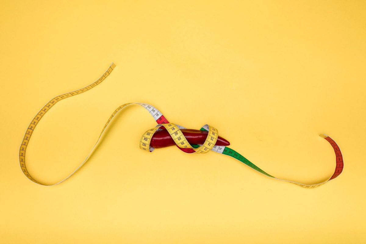 Ruban à mesurer enroulé autour d'un poivron rouge sur fond jaune.