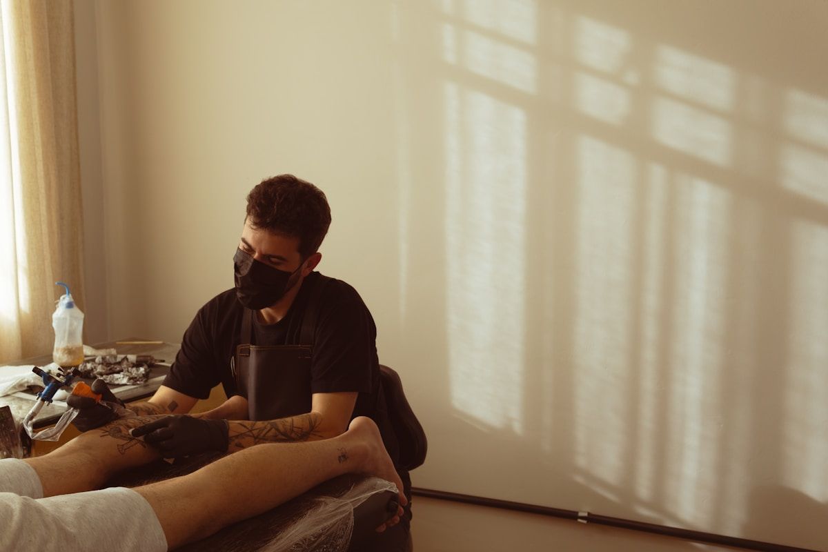 Tatoueur tatoue un client dans un studio de tatouage.