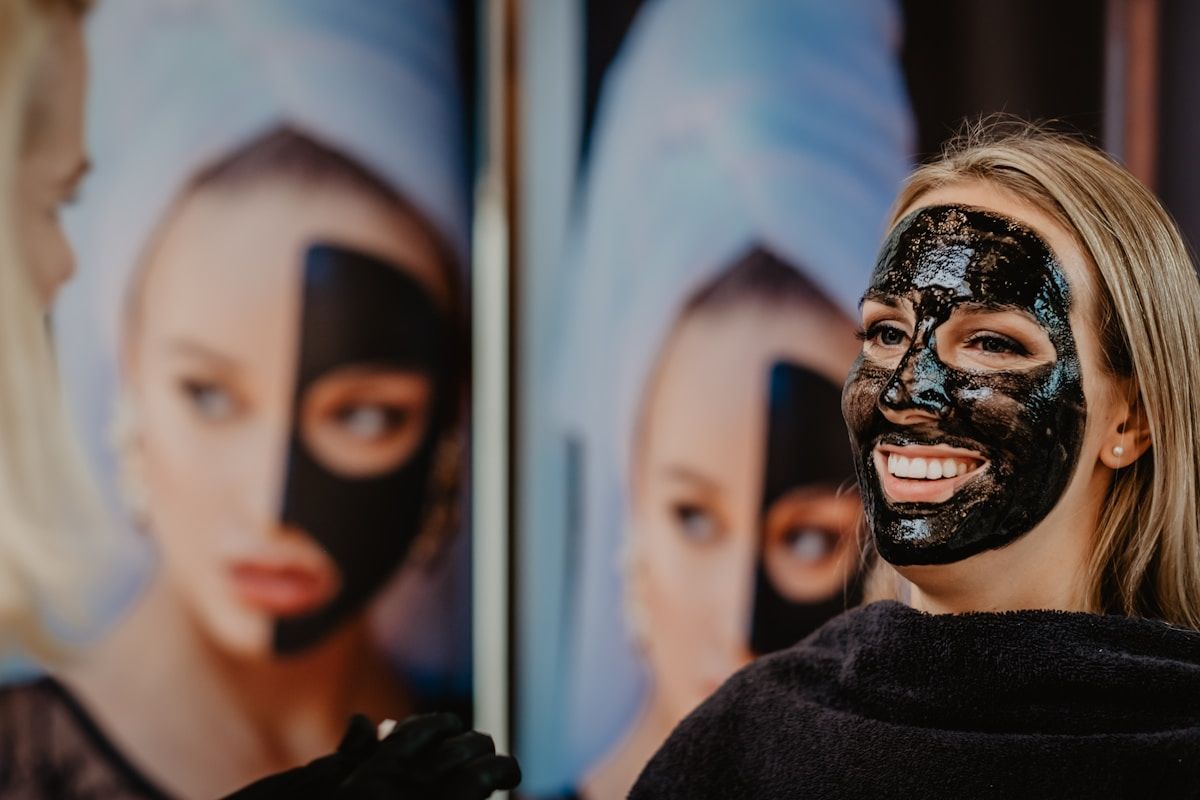 Femme souriante avec un masque facial noir appliqué.