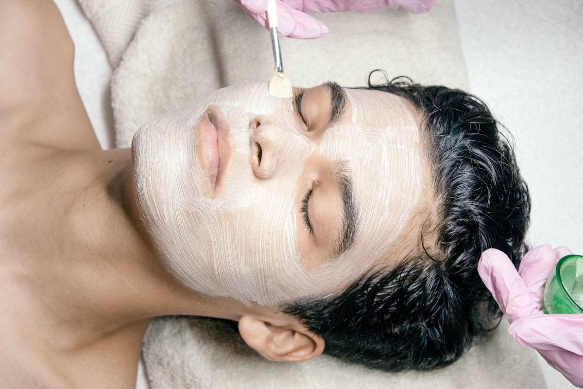 Femme recevant un traitement de beauté facial avec un masque blanc.