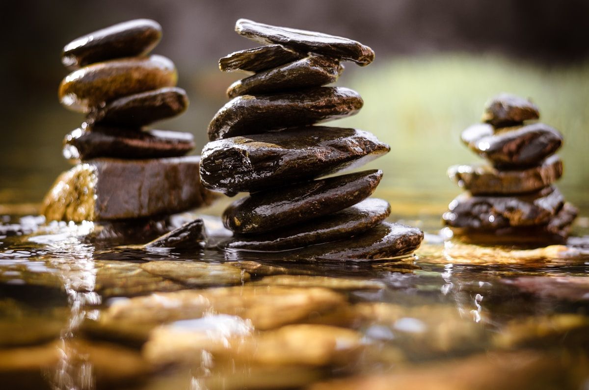 Pierres empilées dans l'eau, reflets dorés, ambiance zen.