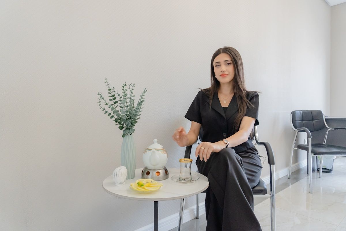 Femme élégante assise dans un bureau moderne avec des plantes et des accessoires.