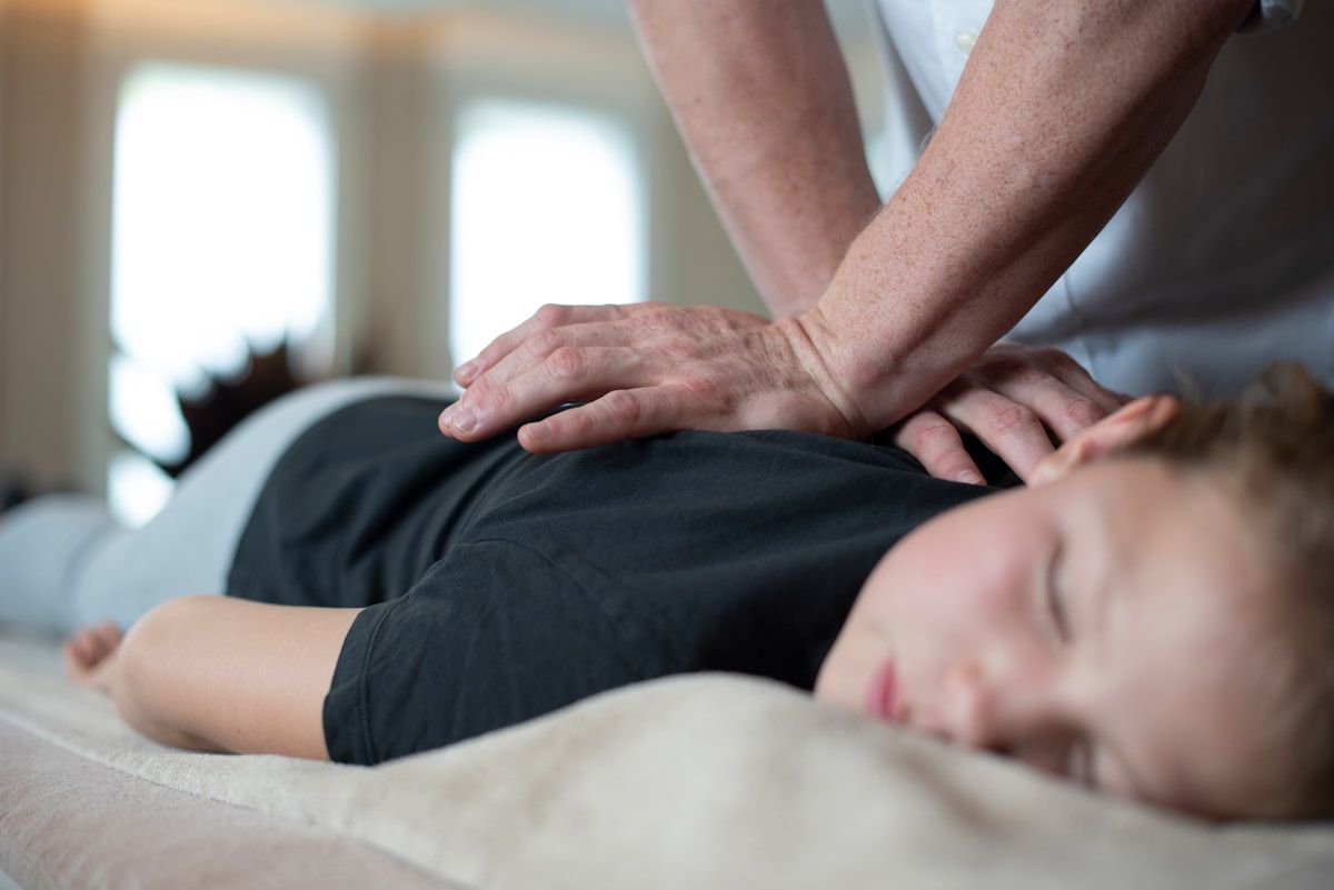 Massage thérapeutique, mains appliquées sur le dos d'une personne allongée.