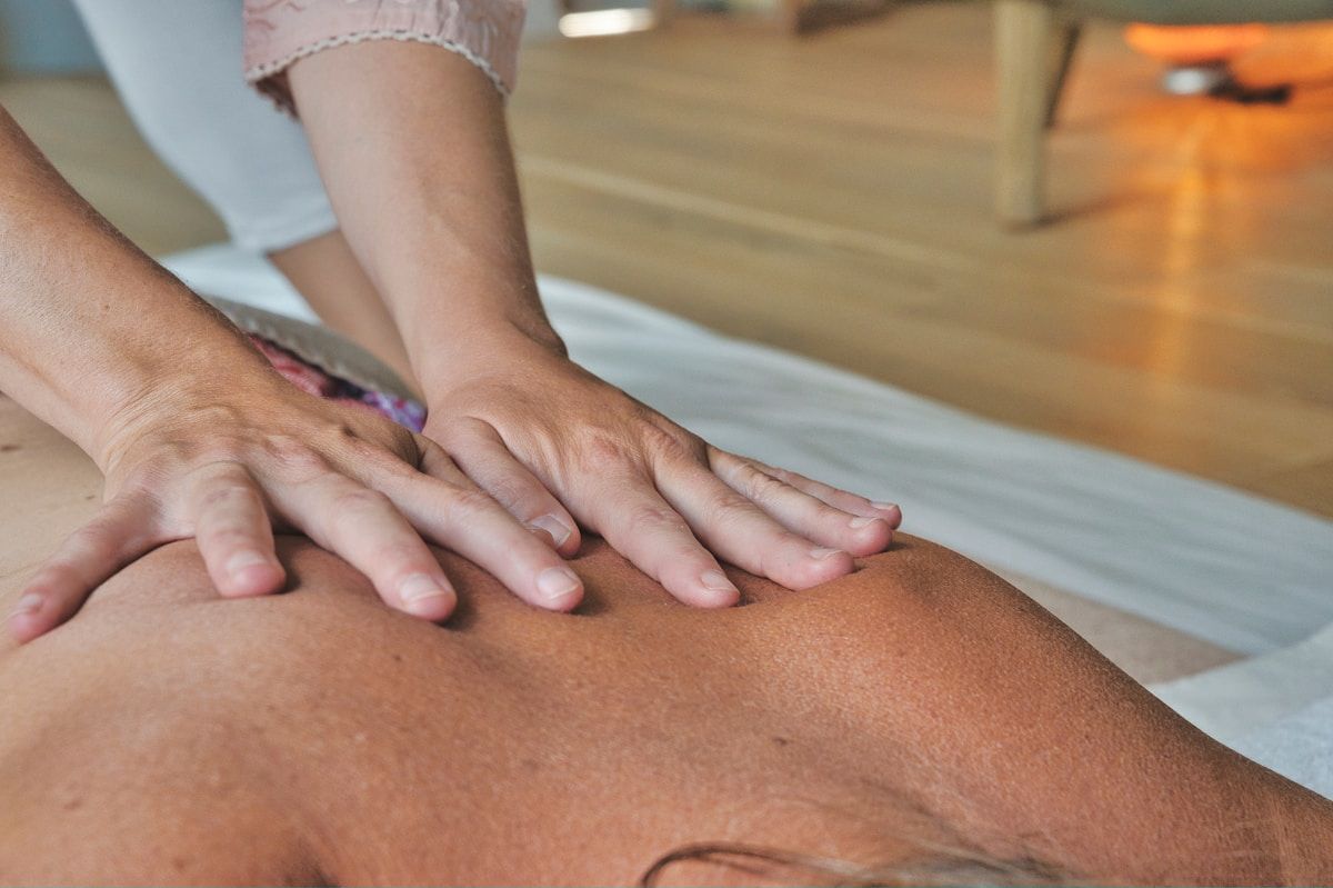 Mains effectuant un massage thérapeutique sur le dos d'une personne.