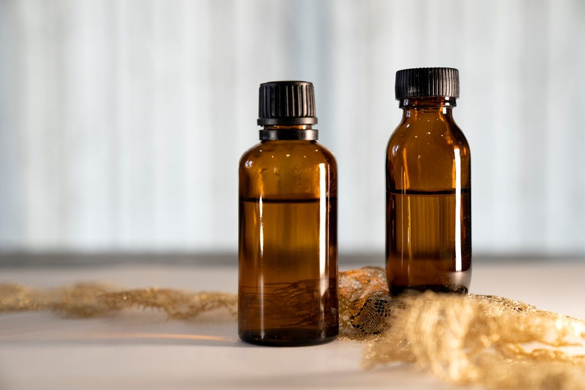 Deux bouteilles d'huile essentielle ambrée sur une surface texturée.