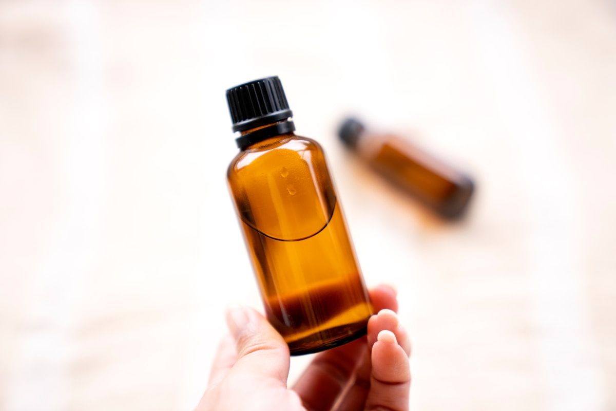 Flacon d'huile essentielle ambre dans une main.