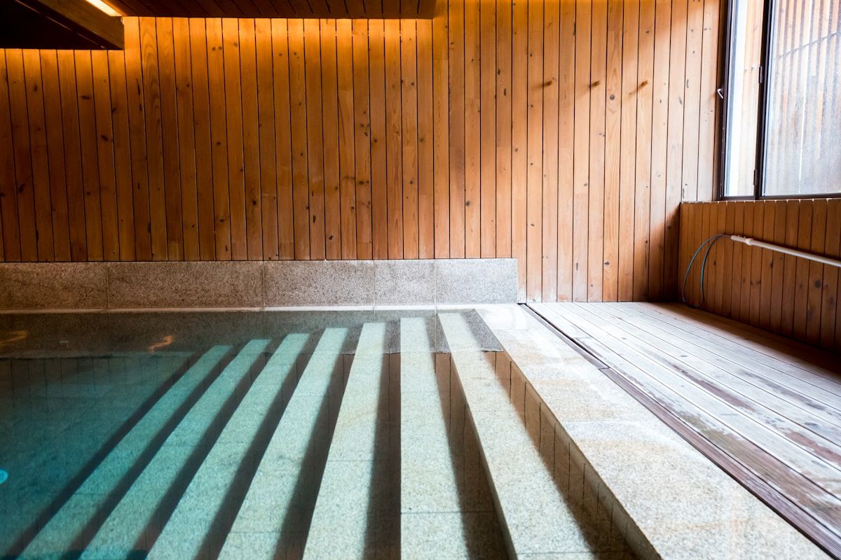 Piscine intérieure en bois et pierre avec escaliers.