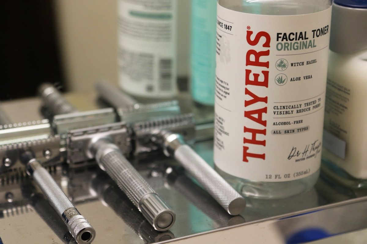 Bouteilles de tonique facial et rasoirs électriques sur une surface.