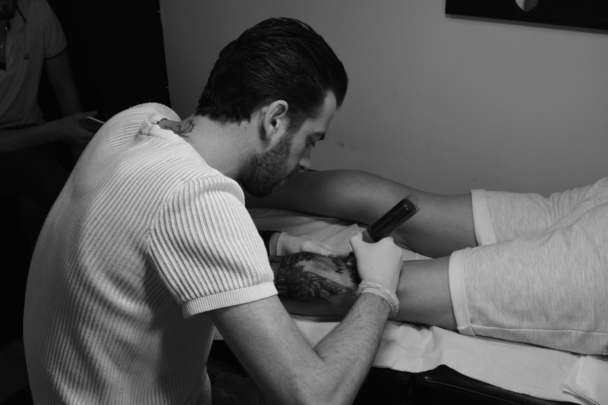 Homme tatoué recevant un traitement médical sur son bras.