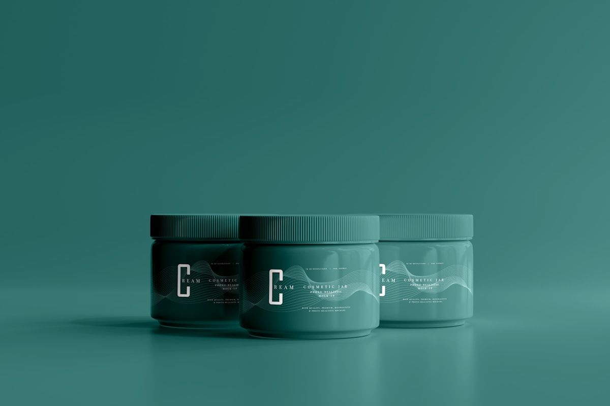 Trois bocaux cosmétiques verts foncés sur fond vert.