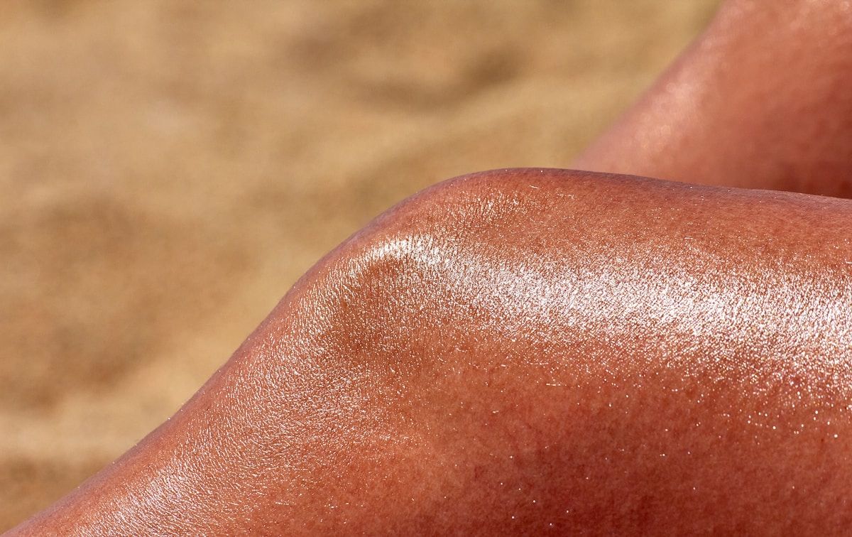 Peau bronzée avec reflets dorés et texture lisse.