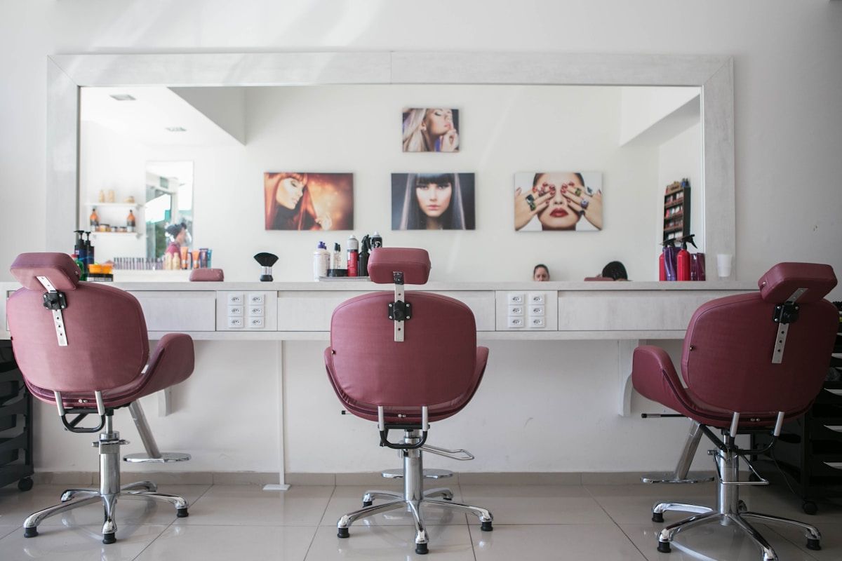 Salon de coiffure moderne avec chaises de coiffure roses et décor minimaliste.