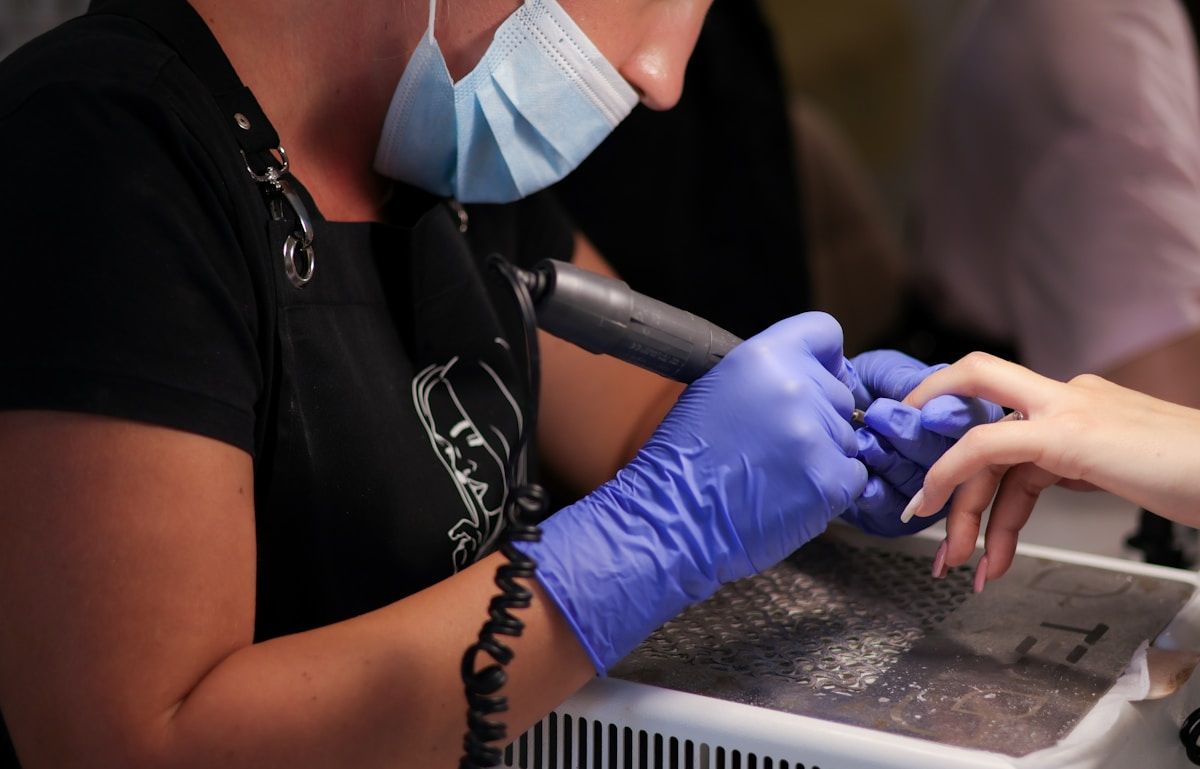 Tatouage professionnel en cours, gants bleus, machine à tatouer.