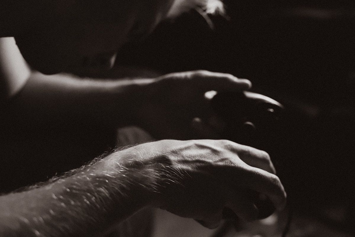 Mains masculines sombres et rugueuses, geste de détresse ou de douleur.