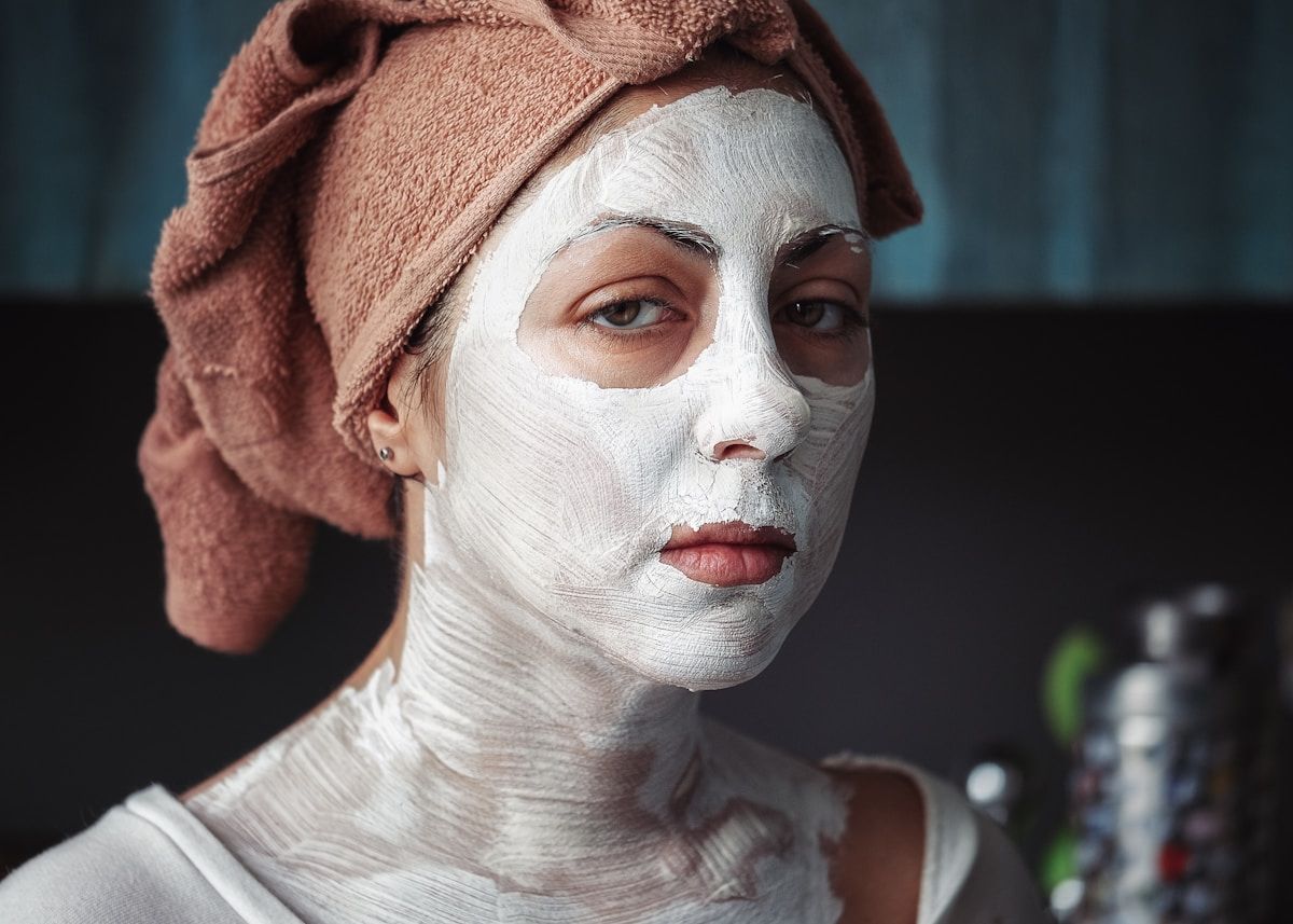 Femme avec un masque facial blanc et un turban rose.