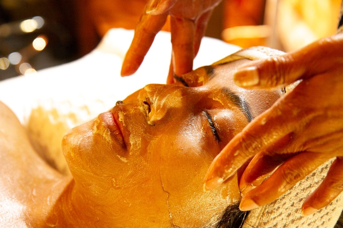 Masque facial doré appliqué sur le visage d'une personne.