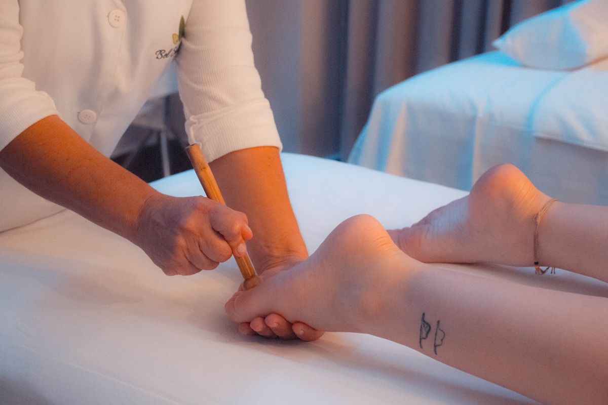 Médecin examinant le pied d'un patient allongé sur un lit.
