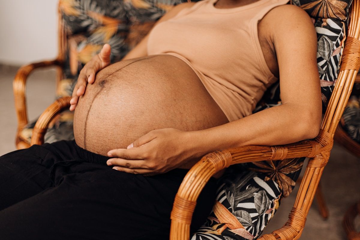 Femme enceinte assise dans un fauteuil en rotin.