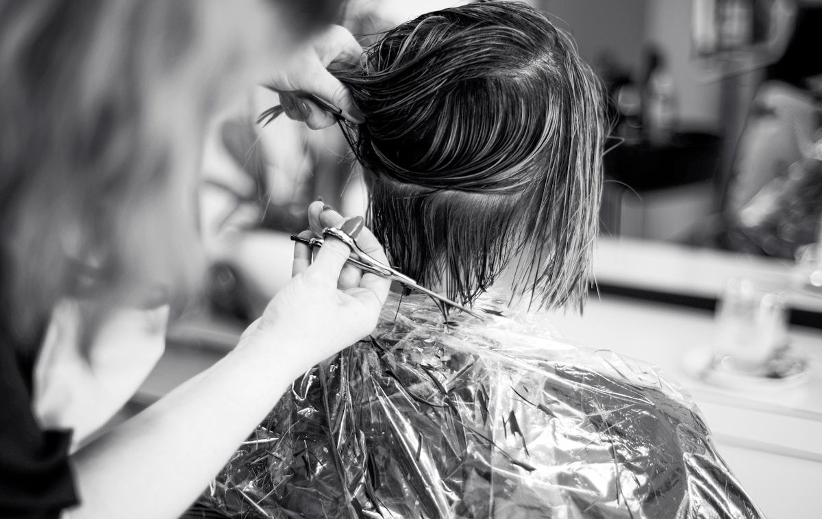 Coiffure en noir et blanc, ciseaux coupant les cheveux.