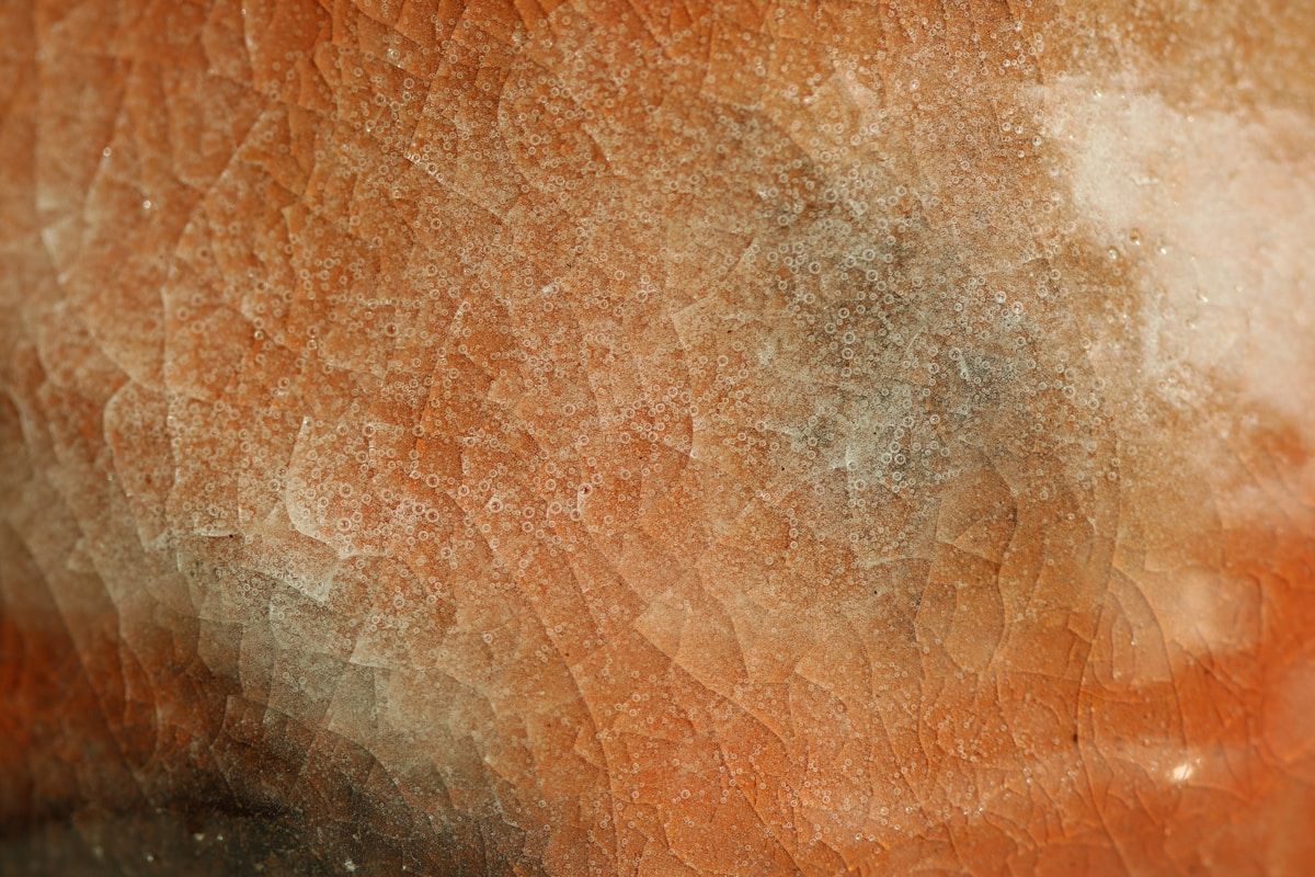 Texture rugueuse et granuleuse de couleur orange et beige.