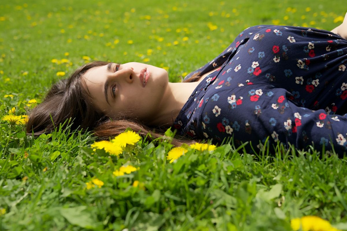 Jeune femme allongée dans un champ de fleurs jaunes.