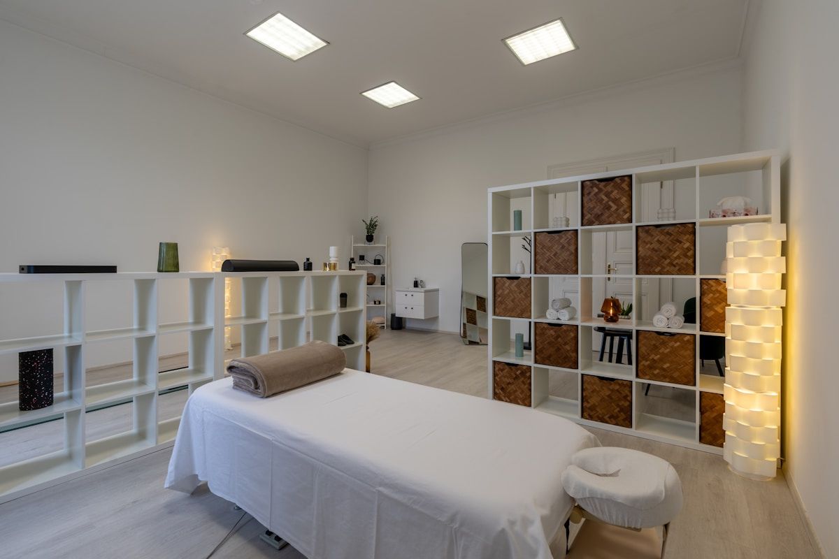 Salle de massage spacieuse et bien équipée avec étagères de rangement.