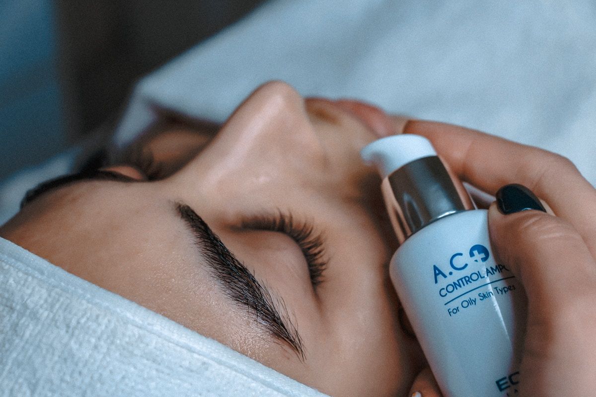 Gros plan d'un visage féminin avec des cils longs et un produit de contrôle de l'acné.