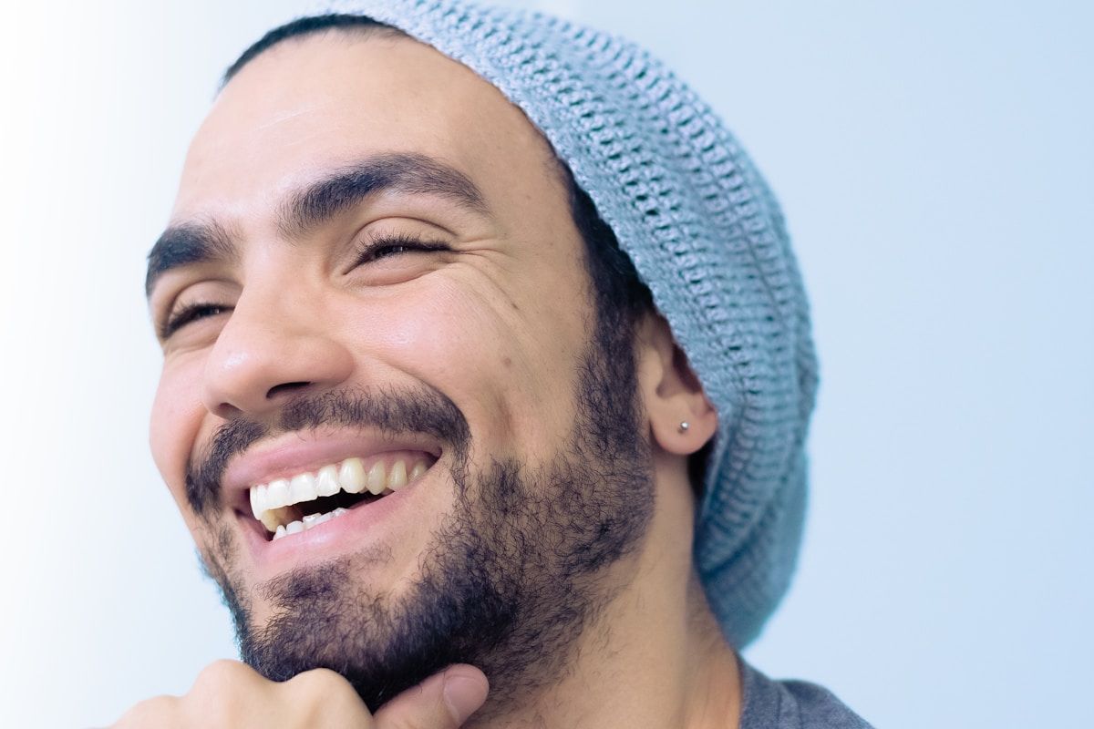 Homme souriant avec un bonnet bleu et une barbe.