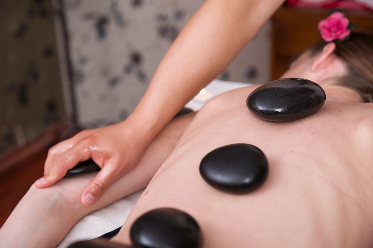 Massage aux pierres chaudes sur le dos d'une personne.