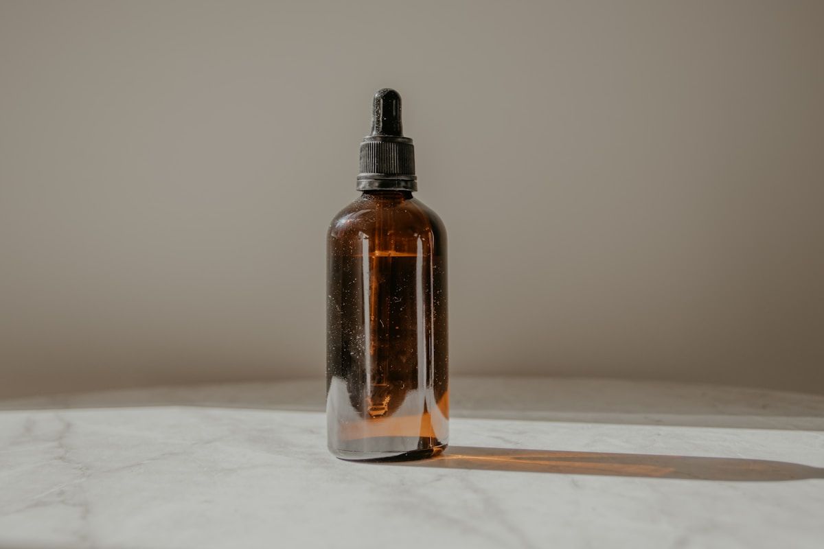 Bouteille en verre ambre avec compte-gouttes, sur surface en marbre.