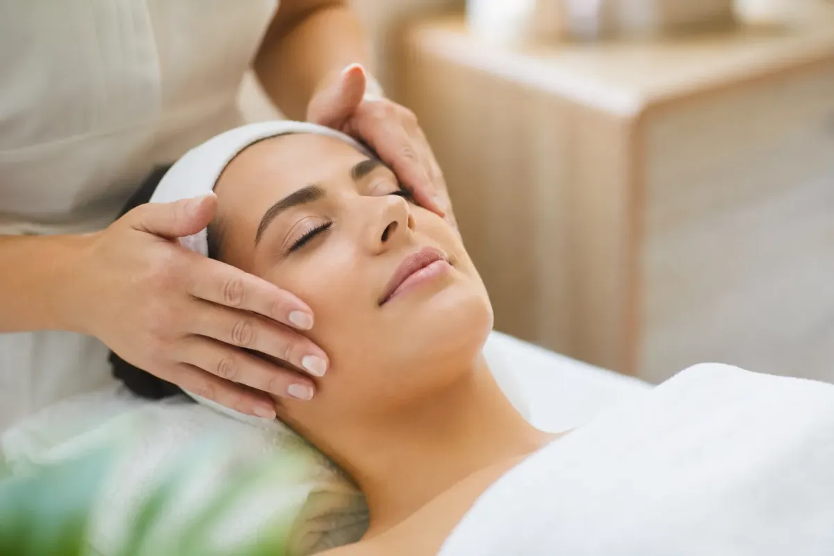 Femme recevant un massage facial relaxant dans un environnement serein.