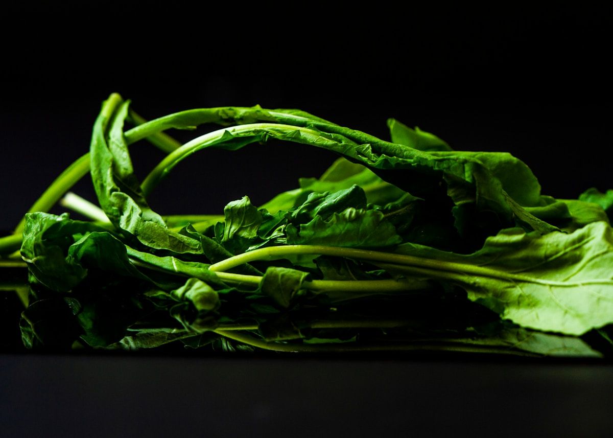 Feuilles de légumes verts fraîches et saines sur fond noir.