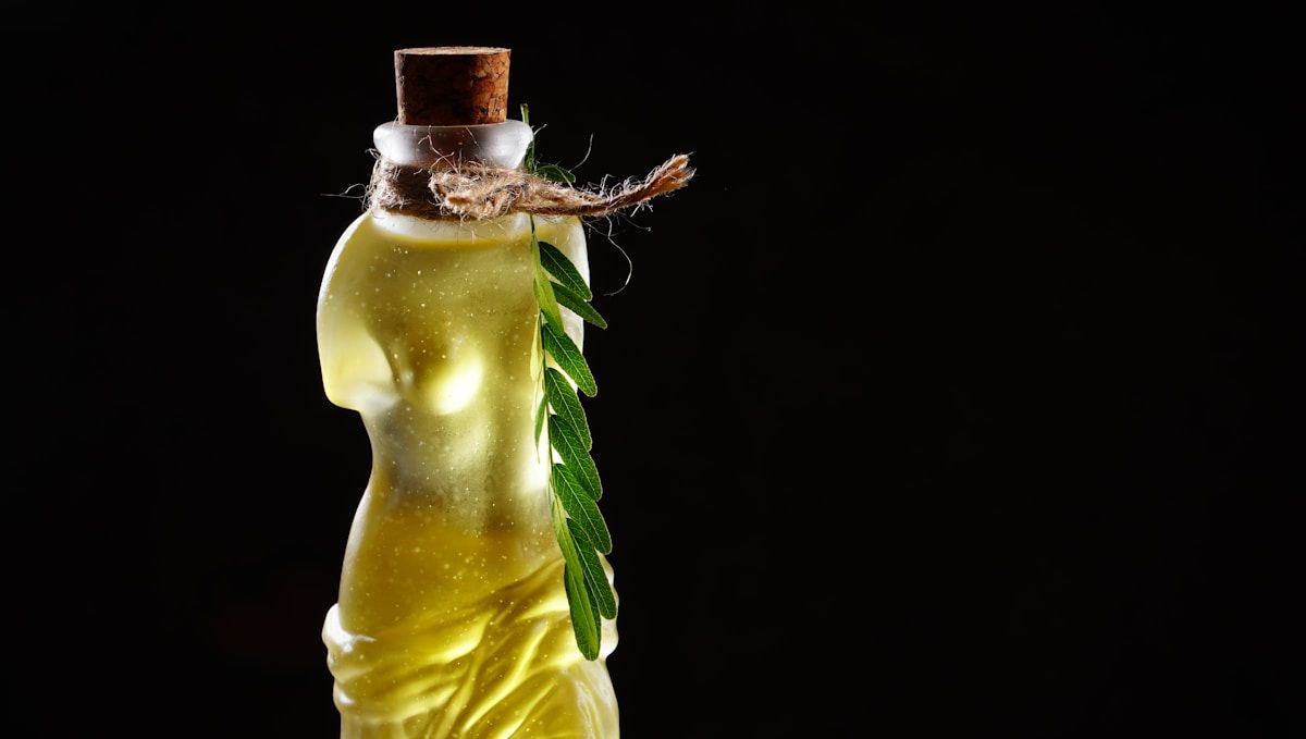 Bouteille de liquide jaune avec bouchon en liège et feuille verte.