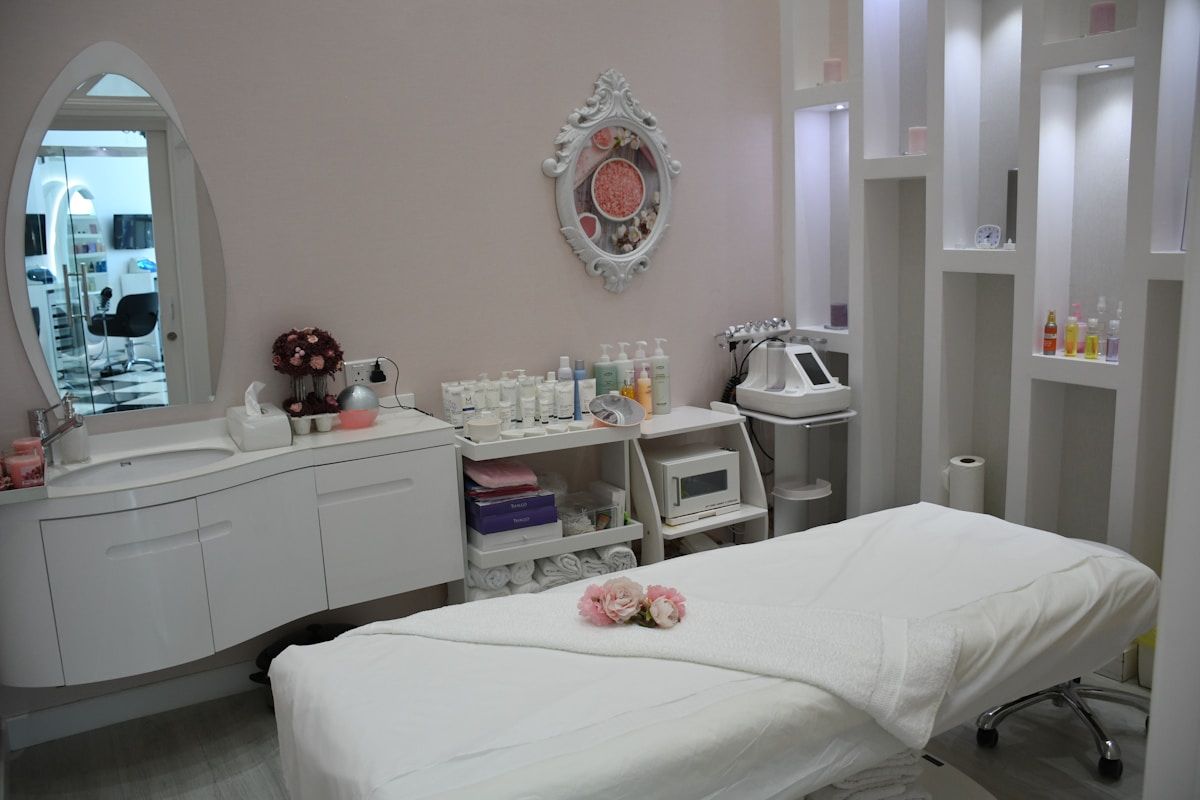 Salle de soins esthétiques avec table de massage, produits cosmétiques et miroir décoratif.
